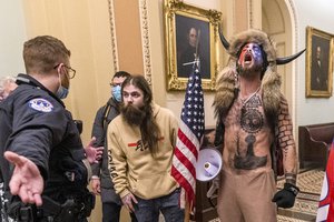 FILE - In this Wednesday, Jan. 6, 2021 file photo, supporters of President Donald Trump, including Jacob Chansley, right with fur hat, are confronted by Capitol Police officers outside the Senate Chamber inside the Capitol in Washington.  Right-wing extremism has previously mostly played out in isolated pockets of America or in smaller cities.