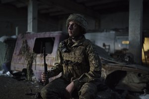 A Ukrainian soldier poses for a photo as he sits in a fighting position on the line of separation from pro-Russian rebels, near Donetsk, Ukraine, Monday, May 3, 2021