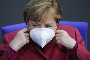 In this file photo dated Thursday, Oct. 29, 2020, German Chancellor Angela Merkel adjusts her face mask at the parliament Bundestag, in Berlin, Germany.