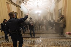 In this Jan. 6, 2021, file photo, smoke fills the walkway outside the Senate Chamber as supporters of President Donald Trump are confronted by U.S. Capitol Police officers inside the Capitol in Washington.