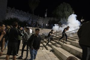 Palestinians react to stun grenades fired by Israeli police to clear the Damascus Gate to the Old City of Jerusalem after clashes at the Al-Aqsa Mosque compound, Friday, May 7, 2021. Palestinian worshippers clashed with Israeli police late Friday at the holy site sacred to Muslims and Jews, in an escalation of weeks of violence in Jerusalem that has reverberated across the region. (AP Photo/Maya Alleruzzo)