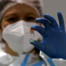 A medical worker poses with a vial of the Sinopharm’s COVID-19 vaccine.