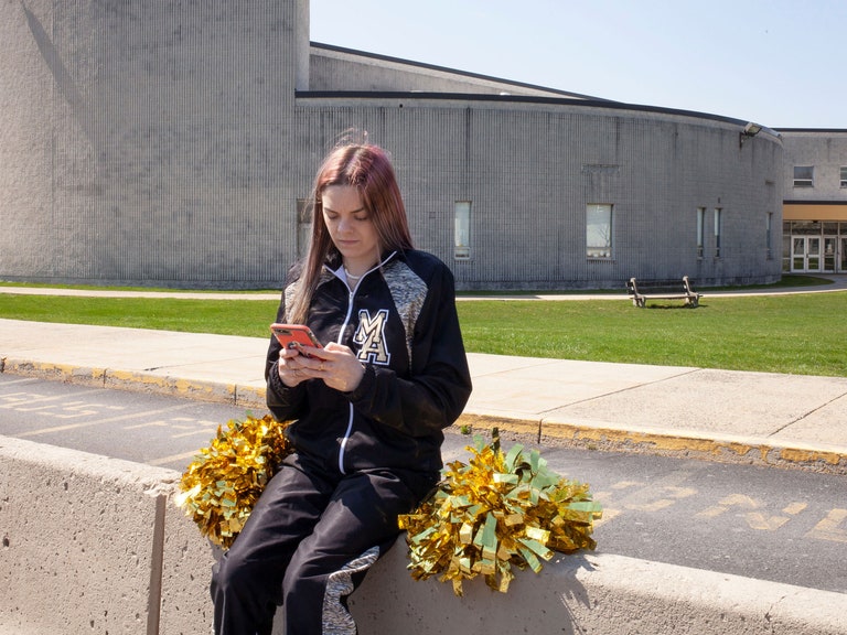 Brandi Levy sits outside of the high school in her cheer uniform.