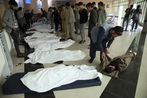 Afghan men try to identify the dead bodies at a hospital after a bomb explosion near a school west of Kabul, Afghanistan, Saturday, May 8, 2021.