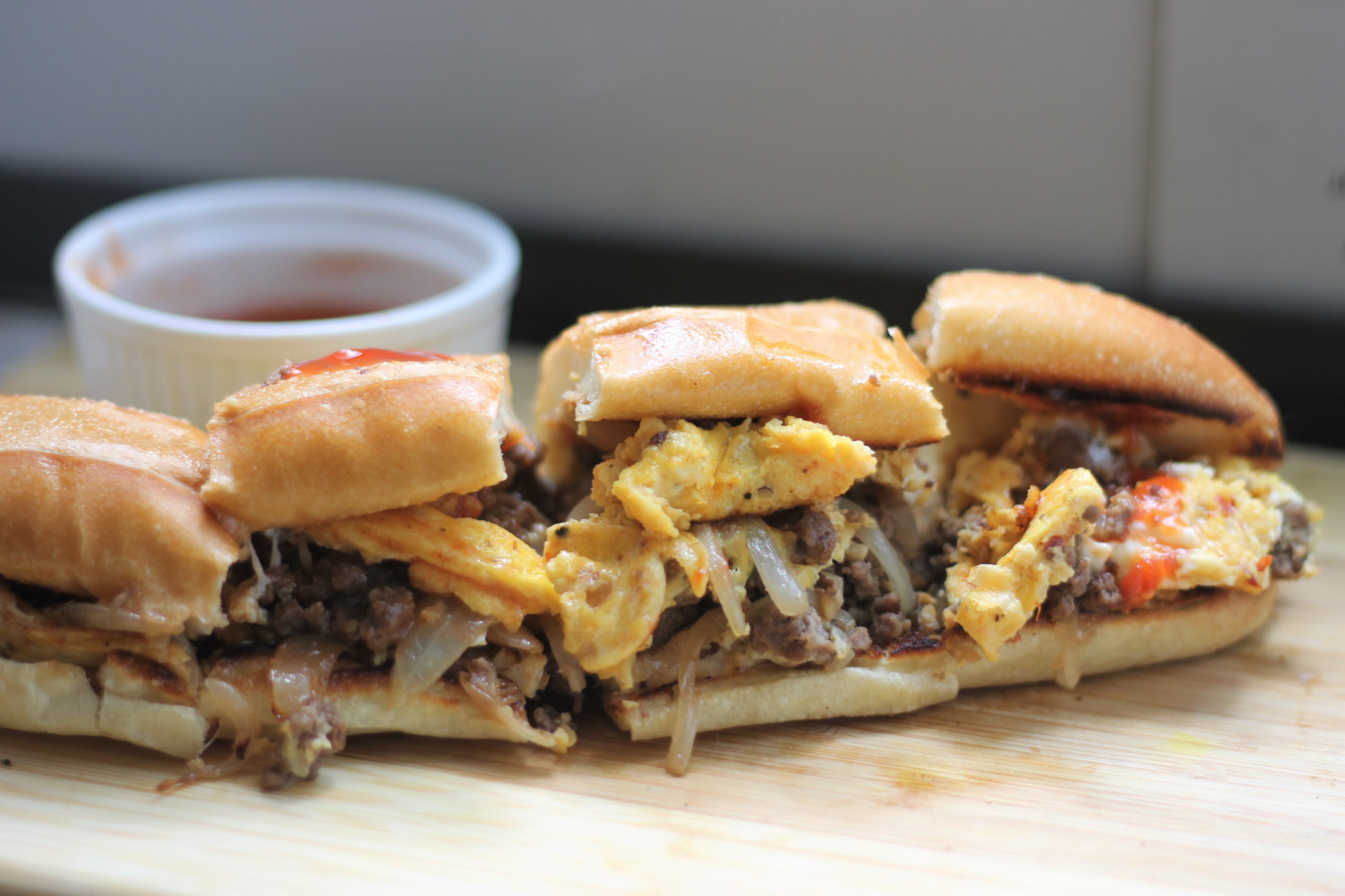 A beef and egg sandwiched placed on a wooden tray