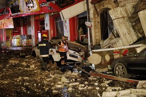 Firefighters inspect destroyed buildings after it was hit by Israeli airstrikes, in Gaza City, early Wednesday, May 12, 2021.