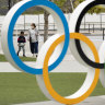 A mother and a boy walk by a display of the Olympic rings at the Japan Olympic Museum in Tokyo.