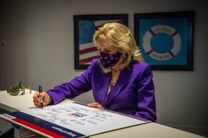 First Lady Dr. Jill Biden signs a Military OneSource info-board after a facility tour with Charlene Austin and Hollyanne Milley, in Arlington, Virginia, April 7, 2021