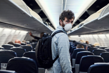 Shot of a young man wearing a mask and boarding an plane