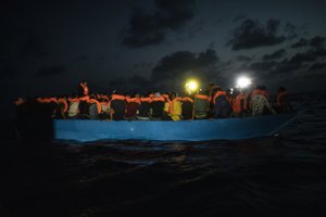 File - Dozens of migrants from different nationalities, mainly Somalia, Egypt and Morocco, including 14 minors and 4 women, wait to be assisted by a team of aid workers of the Spanish NGO Open Arms, after spending more than 20 hours at sea when fleeing Libya on board a precarious wooden boat, in international waters, in the Central Mediterranean sea, Tuesday, Sept. 8, 2020.