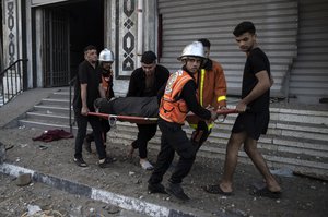 Palestinian rescuers evacuate an elderly woman from a building following Israeli airstrikes on Gaza City, Wednesday, May 12, 2021.