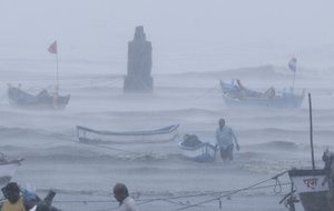 A fisherman waits for help as he tries to move a fishing boat to a safer ground on the Arabian Sea coast in Mumbai, India, Monday, May 17, 2021.