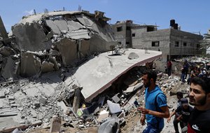 People inspect the rubble of a destroyed residential building which was hit by Israeli airstrikes, in Gaza City, Wednesday, May 12, 2021.