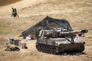 Israeli soldiers carry a box next to their mobile artillery piece near the border with Lebanon, northern Israel, Wednesday, Aug. 26, 2020