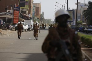 File - Soldiers patrol outside the Splendid Hotel, following an attacked by suspected militants in Ouagadougou, Burkina Faso, Saturday, Jan. 16, 2016.