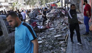 People inspect the rubble of the destroyed Abu Hussein building that was hit by an Israeli airstrike early morning, in Gaza City, Wednesday, May 19, 2021. Hussein, an al-Aqsa radio reporter, was killed during the attack.