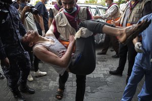 A Palestinian carries a wounded man into the Shifa hospital following Israeli airstrikes on Gaza City, Thursday, May 20, 2021