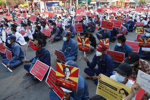 Government employees from the Mandalay City Development Committee hold placards with images of deposed Myanmar leader Aung San Suu Kyi during an anti-coup rally in front of the Mandalay railway station in Mandalay, Myanmar on Monday, Feb.