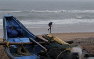 A man walks holding an umbrella during a drizzle at the Puri beach on the Bay of Bengalcoast in Odisha, India, Monday, May 24, 2021.