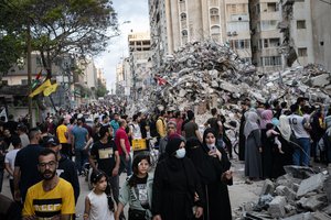 A family passes the rubble from a building previously destroyed in an air-strike following a cease-fire reached after an 11-day war between Gaza's Hamas rulers and Israel, in Gaza City, Friday, May 21, 2021.