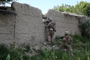 File - U.S. Marine Corps Capt. Scott Stewart, left, the commanding officer of Weapons Company, 1st Battalion, 7th Marine Regiment, scans for suspicious activity through a hole in a mud wall during a mission in Helmand province, Afghanistan, April 17, 2014.