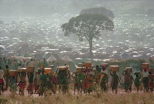 In this Tuesday, May 17, 1994 file photo, refugees who fled the ethnic bloodbath in neighboring Rwanda carry water containers back to their huts at the Benaco refugee camp in Tanzania, near the border with Rwanda.