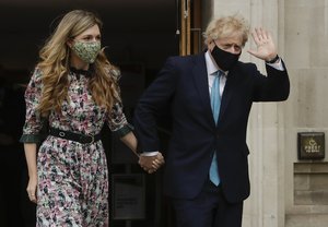 British Prime Minister Boris Johnson arrives at a polling station with his partner Carrie Symonds to cast his vote in local council elections in London, Thursday May 6, 2021.