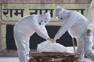 Relatives wearing PPE kits perform rituals for a COVID-19 victim in Jammu, India, 19 April 2021.