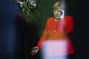 Angela Merkel makes a phone call as the walks through the chancellery  to welcome Czech President Milos Zeman