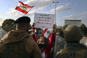 An anti-government protester hols up a placard with Arabic that reads: "The problem is not in the system or the constitution