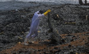 A Sri Lankan navy soldier hauls debris washed ashore from the burning Singaporean ship MV X-Press Pearl which is anchored off Colombo port at Kapungoda, out skirts of Colombo, Sri Lanka, Thursday, May 27, 2021