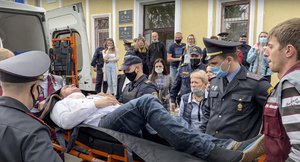 In this image distributed by Radio Free Europe / Radio Liberty, agents and paramedics introduce Stsiapan Latypau, a Belarusian activist who tried to commit suicide during a court hearing protesting political repression, into an ambulance in Minsk, Belarus