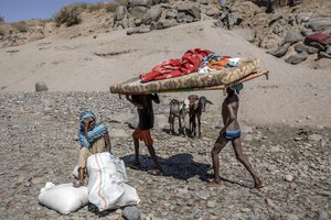 Tigray refugees who fled the conflict in the Ethiopia's Tigray carry their furniture on the banks of the Tekeze River on the Sudan-Ethiopia border, in Hamdayet, eastern Sudan, Tuesday, Dec. 1, 2020.