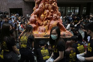 University students clean the "Pillar of Shame" statue, a memorial for those killed in the 1989 Tiananmen crackdown, at the University of Hong Kong, Friday, June 4, 2021