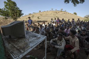 Tigranyan men who fled the conflict in Ethiopia's Tigray region, watch the news on a television, at Umm Rakouba refugee camp in Qadarif, eastern Sudan, Saturday, Dec. 5, 2020.