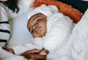 Black baby lying on comfortable bed