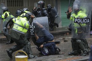 A police officer bears down on an anti-government protester during clashes in Bogota, Colombia, Wednesday, June 9, 2021