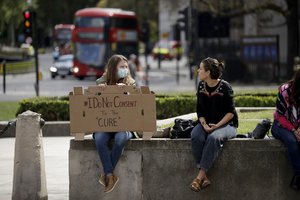 A coronavirus anti-lockdown protester holds a placard in Parliament Square, London, Saturday, May 2, 2020