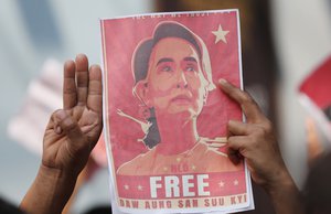 In this Feb. 8, 2021, file photo, Myanmar nationals living in Thailand hold pictures of Myanmar leader Aung San Suu Kyi gesture with a three-fingers salute, a symbol of resistance, as they protest in front of the Myanmar Embassy in Bangkok, Thailand