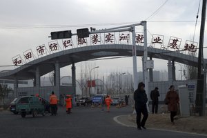 Residents pass by the entrance to the "Hotan City apparel employment training base" where Hetian Taida Apparel Co. has a factory in Hotan in western China's Xinjiang region