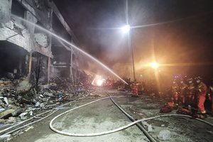 Firefighters work at the site of buildings damaged after a tanker truck explosion on a highway in Wenling, in eastern China's Zhejiang Province