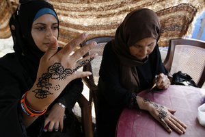 A Palestinian woman demonstrates the painting of a traditional henna tattoo at the Palestinian Heritage Exhibition in the town of Khan Yunis, in the southern Gaza Strip on October 16, 2012. Palestinians attend the Heritage Exhibition every year to remember the ancient civilizations. At the festival, Palestinian women paint henna tattoos on each other a on the second day of the festival.Photo by Ahmed Deeb / WN