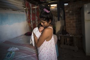 A Venezuelan migrant holds her 20-day-old daughter Eimy, after receiving a donated bag with food during the new coronavirus emergency, in the outskirts of Lima, Peru, Wednesday, April 22, 2020. The food was donated by a group which calls itself "For a quarantine without hunger"