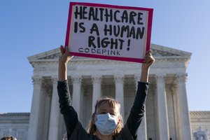 A demonstrator holds a sign in front of the U.S. Supreme Court as arguments are heard about the Affordable Care Act Tuesday, Nov. 10, 2020, in Washington