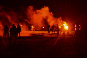 Youths stand in a field during clashes as police tried to break up an unauthorized rave party near Redon, Brittany, Friday June 18, 2021