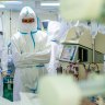 Medics wearing special suits to protect against coronavirus stand next to a patient with coronavirus at the City hospital No. 52 for coronavirus patients in Moscow, Russia, Thursday, June 17, 2021.