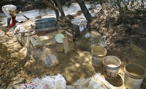 In this Friday Nov. 2, 2012 photo Santos Viriato, lays bath towels on a conveyer to catch the particles during their illegal gold mining in Roodepoort, South Africa