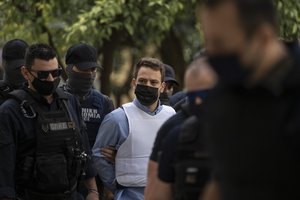 Helicopter pilot Babis Anagnostopoulos, center, escorted by police officers arrives to the prosecutor's office at a court to give evidence, in Athens, Tuesday, June 22, 2021