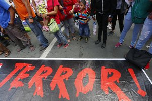 Protesters stand beside a banner during a rally near the Presidential Palace to mark the first year in office of Philippine President Rodrigo Duterte Friday, June 30, 2017