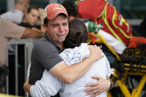 A couple embrace as they wait for news of survivors from a condominium that collapsed, Thursday, June 24, 2021 in Surfside, Fla. Dozens of survivors were pulled out, and rescuers continue to look for more